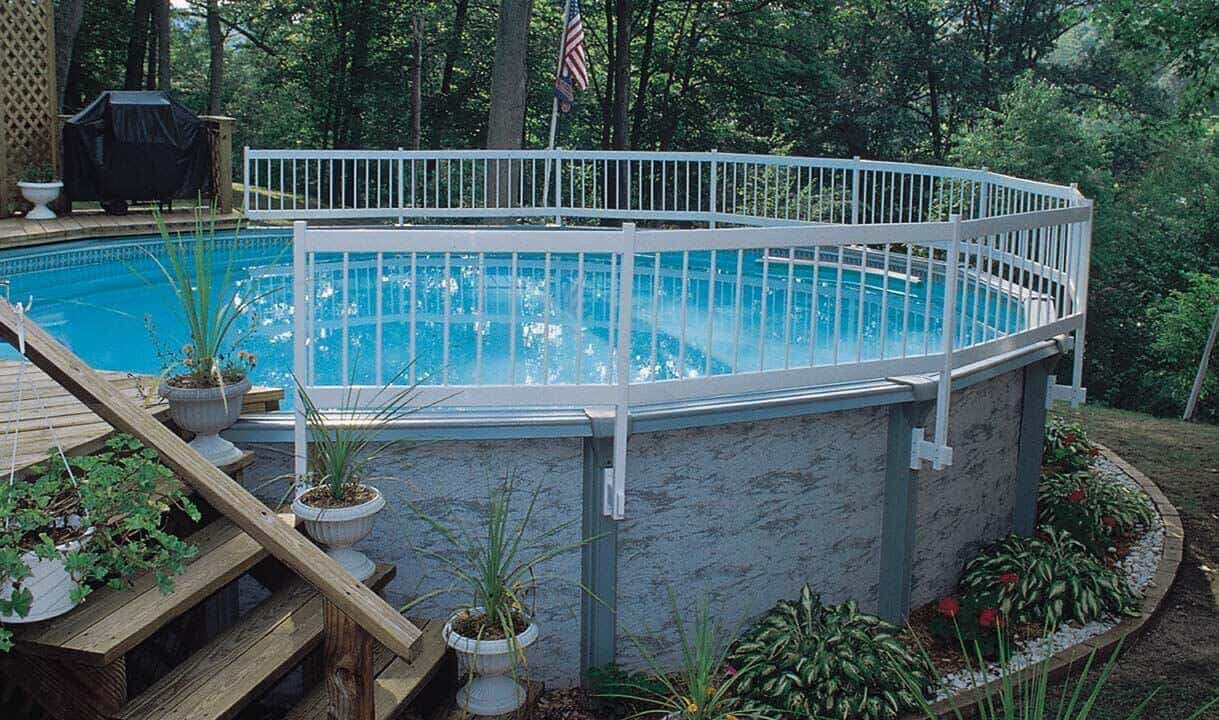 27 Above Ground Pool Landscaping Creative Ideas 16 Circular above ground pool features a white safety fence, wooden deck, and lush potted plants, blending seamlessly into the backyard.