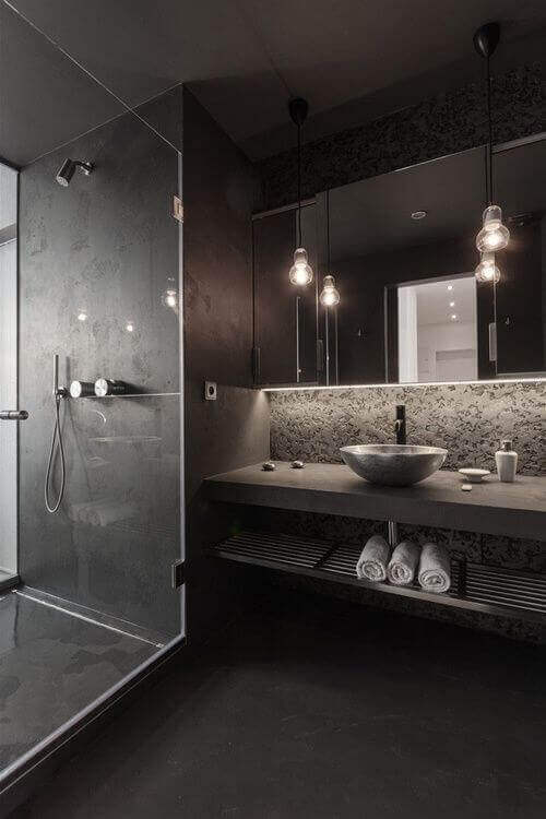 Sleek spa bathroom features dark concrete walls, a floating vanity, and a round metallic vessel sink. Ambient lighting enhances the minimalist design.