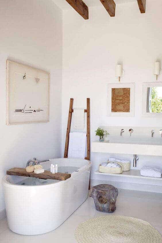Modern spa bathroom with freestanding tub, natural light, whitewashed walls, and wooden accents for a serene atmosphere.