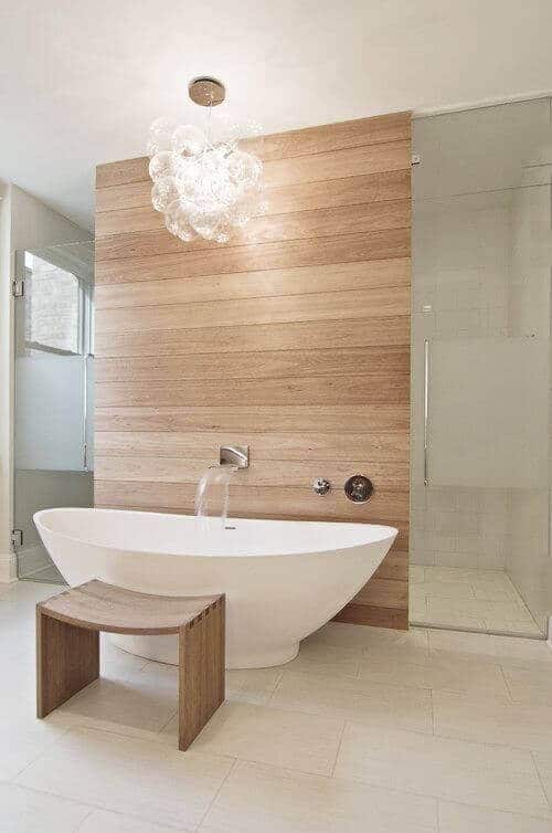 Modern spa bathroom with a freestanding tub, wood accent wall, glass shower, and calming light-colored tiles, creating a minimalist vibe.