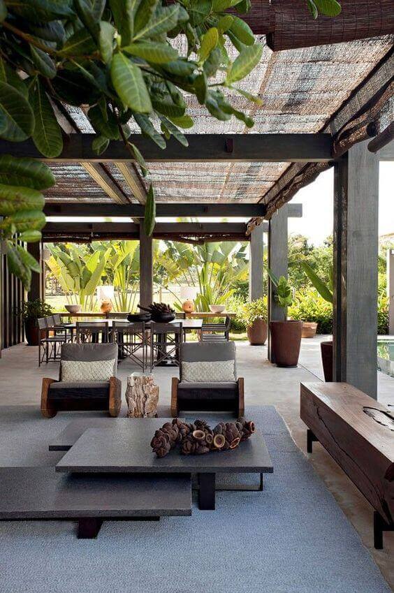Stylish covered patio featuring a wooden pergola, comfortable seating, and lush greenery, ideal for outdoor living and gatherings.