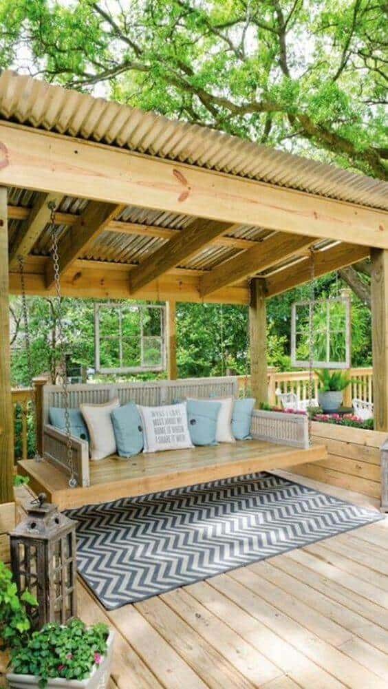 {{post_main_keyword}} features a wooden gazebo with a swing, blue cushions, and a geometric rug, creating a cozy and inviting outdoor space.