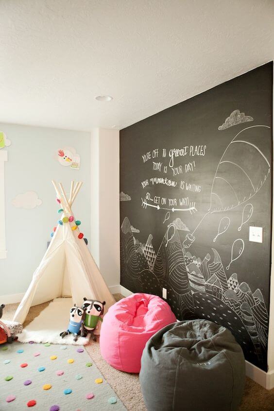 Spacious basement playroom with a white teepee, polka dot rug, chalkboard wall, and vibrant bean bags, designed for creative activities.