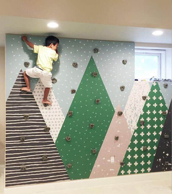 Colorful indoor rock climbing wall for kids, featuring triangular panels in muted shades, promoting safe climbing and physical activity.