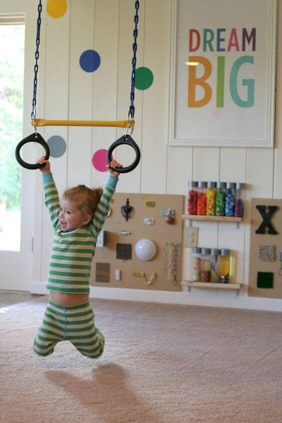 Bright basement playroom with a ceiling swing, polka dot accent wall, soft carpet, and craft supplies, perfect for kids' activities.