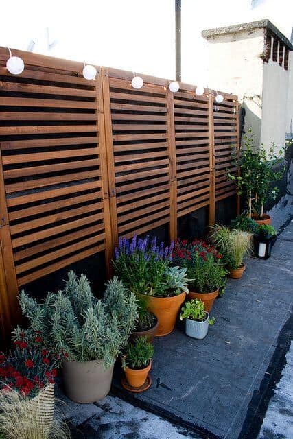 Garden privacy screens provide seclusion and airflow, complemented by potted lavender, rosemary, and ornamental grasses in terracotta pots.