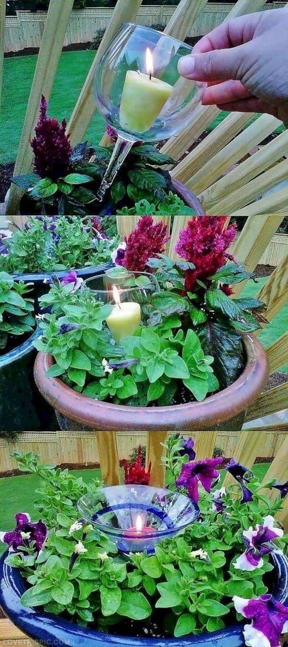 Candle planter with petunias and ornamental plants in ceramic pots, set against a green lawn and wooden fence, creates a cozy outdoor space.