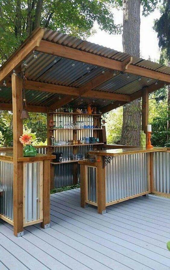 Outdoor bar made of wood and galvanized metal, featuring two counter spaces, a corrugated roof, and stylish glassware display. Perfect for cozy backyard gatherings.