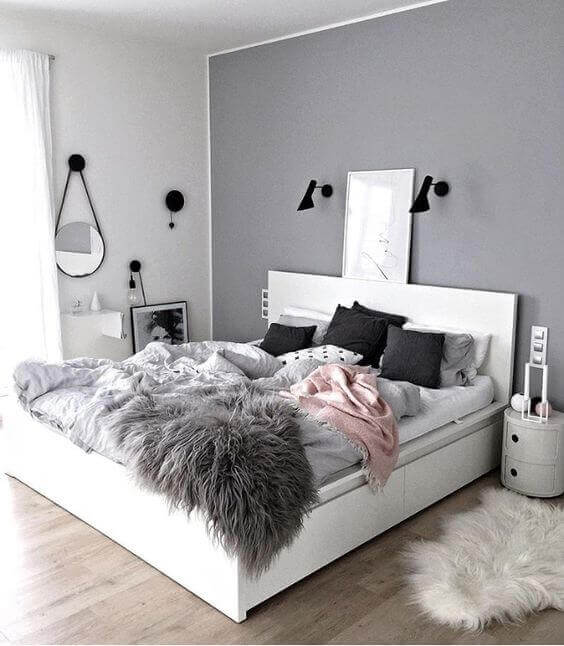 Modern Scandinavian bedroom with a gray accent wall, white platform bed, and cozy textiles, featuring a warm, inviting atmosphere.