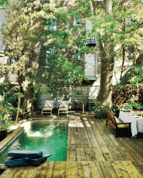 Cozy small backyard deck made from treated pine, surrounded by lush greenery, featuring lounge chairs and a rustic dining setup.