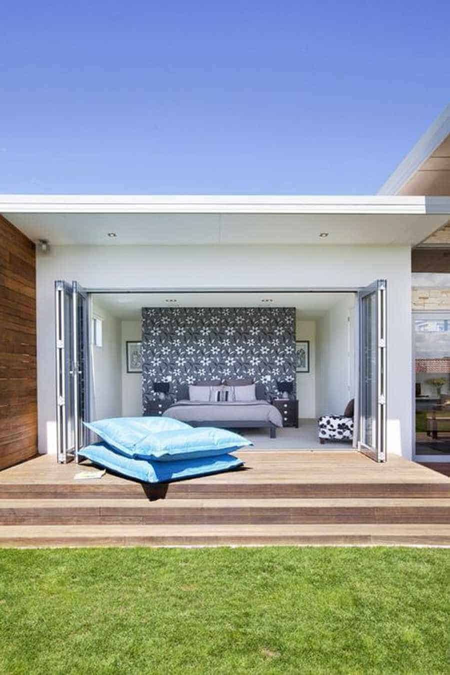 Open layout deck design features a wooden deck extending into a green lawn, connecting indoor and outdoor living spaces.