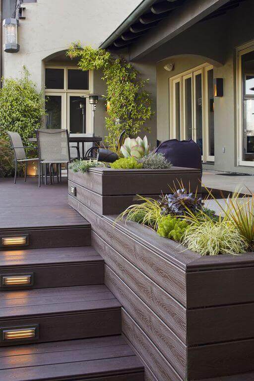 Multi-level deck design with dark wooden decking, integrated planters, and LED-lit steps, creating an inviting outdoor living space.