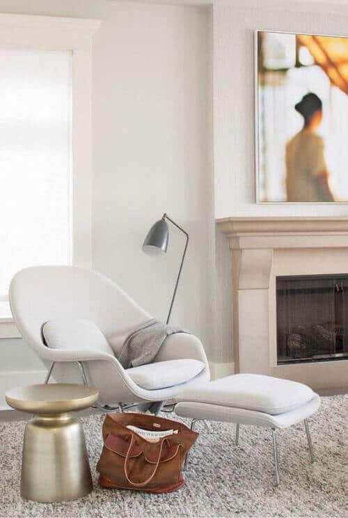 Cozy reading nook featuring a modern lounge chair and ottoman, accented by a gold table and soft rug, perfect for relaxation and reading.