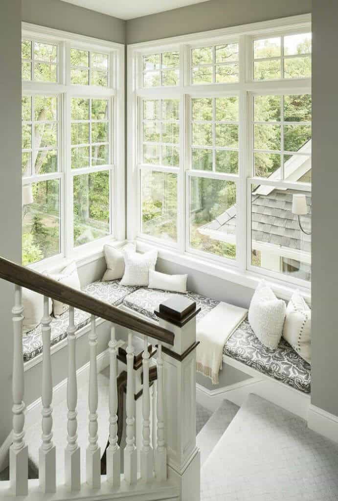 Cozy reading nook with a cushioned L-shaped window seat, plush pillows, and natural light, perfect for relaxing with books.
