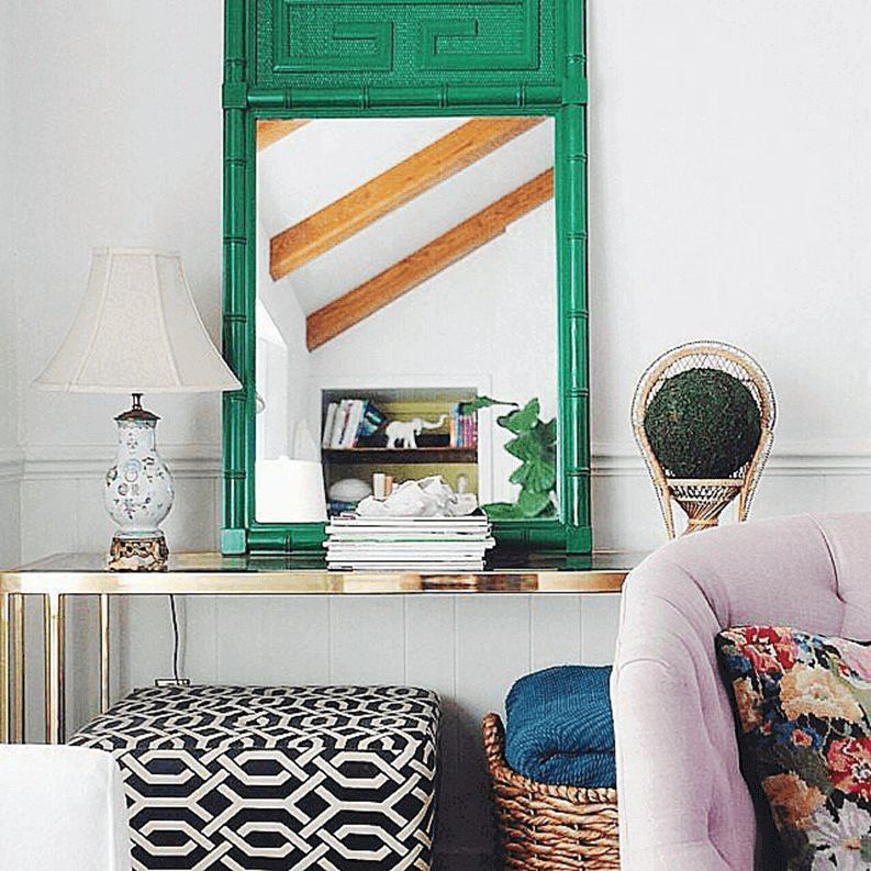 27 Contemporary Living Room Ideas for a Modern Haven Space 11 Ornate green frame mirror above a polished console table, with decor items, lamp, and colorful pouf, in a cozy contemporary living room.