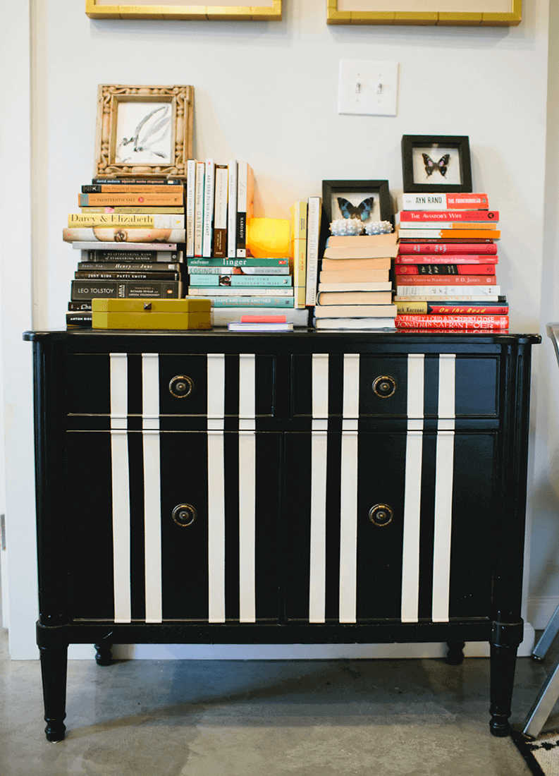 27 Contemporary Living Room Ideas for a Modern Haven Space 12 Sleek black and white dresser with striped cabinet doors, set on a concrete floor, enhancing contemporary living room aesthetics.