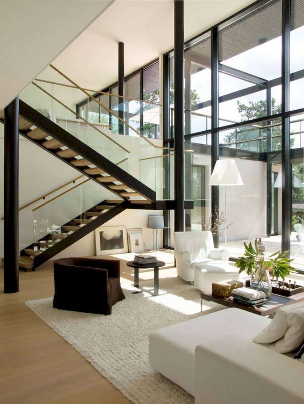 27 Contemporary Living Room Ideas for a Modern Haven Space 14 Spacious contemporary living room with glass walls, minimalist white sectional, dark accent chair, plush rug, and open staircase.