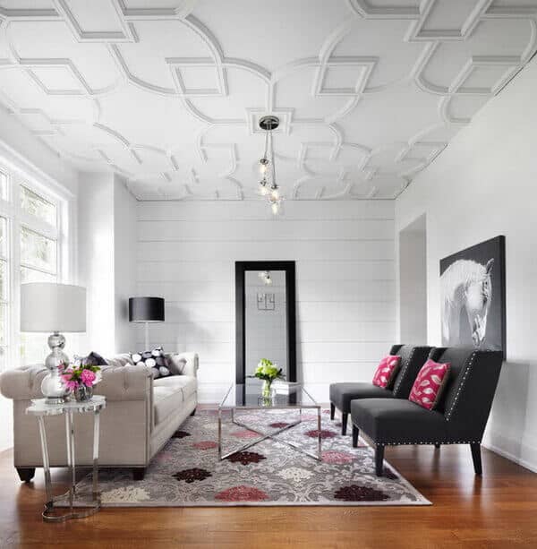 27 Contemporary Living Room Ideas for a Modern Haven Space 19 Contemporary living room with coffered ceiling, light gray sofa, black accent chairs, floral rug, glass coffee table, and hardwood flooring.
