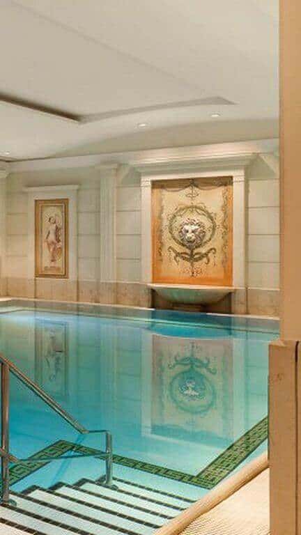 Indoor swimming pool design featuring a serene 10-meter pool with elegant stone tiles, mosaic edges, and climate control for year-round comfort.