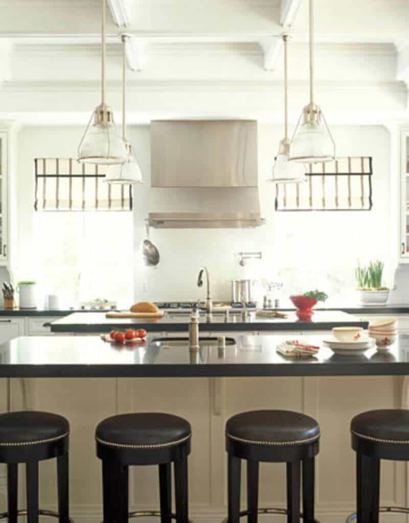 Modern kitchen featuring two spacious islands with dark granite surfaces, white cabinetry, and elegant pendant lighting. Ideal for cooking and dining.