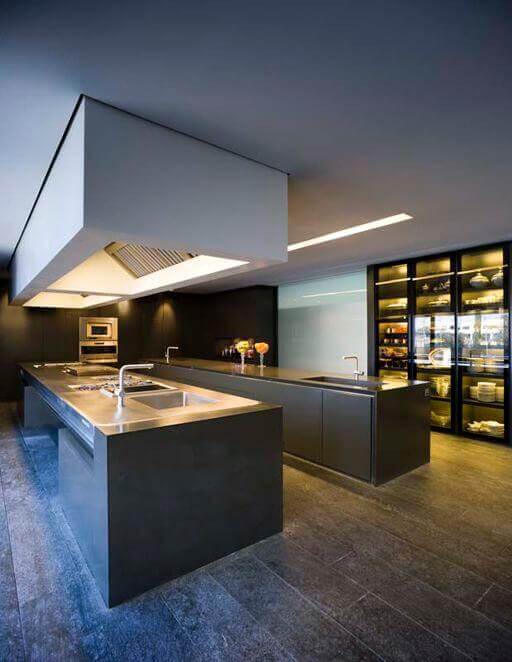 Spacious modern kitchen featuring two central islands, sleek dark cabinetry, stainless steel countertops, and contemporary recessed lighting.