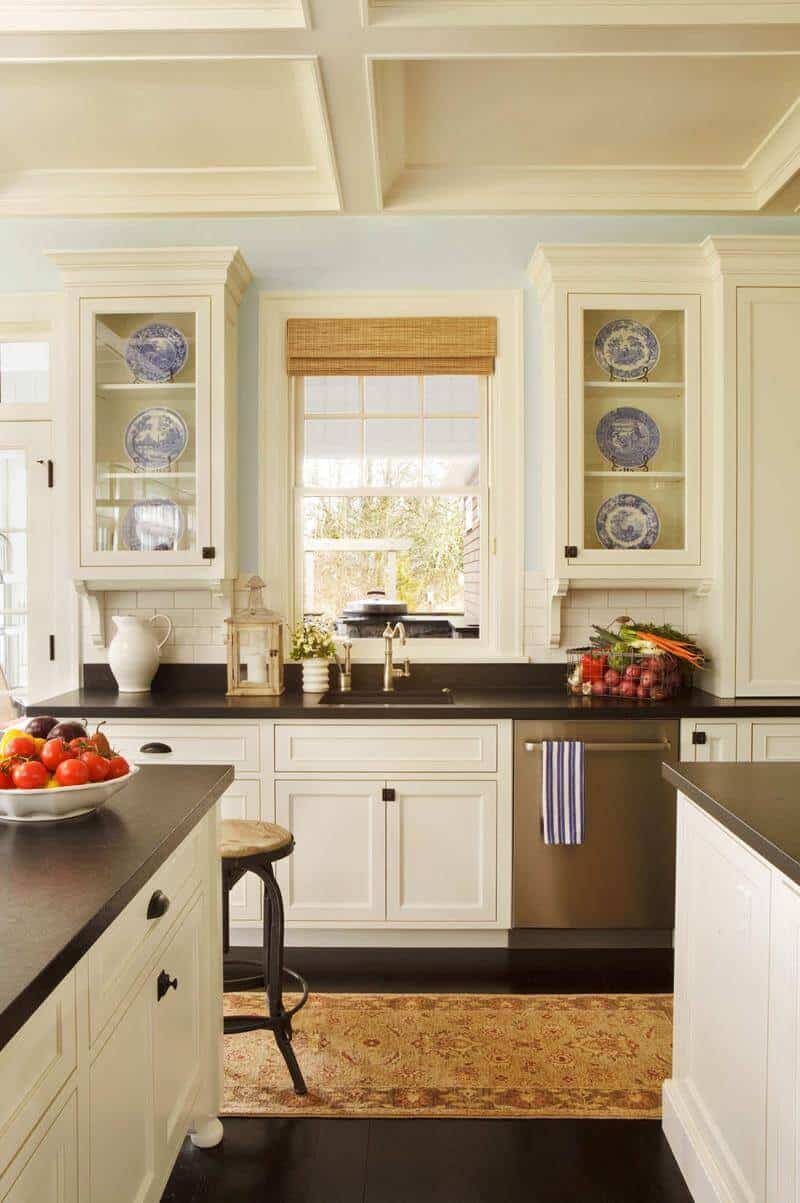 Modern kitchen featuring a double island layout with light blue walls, white cabinetry, dark granite countertops, and elegant coffered ceiling.