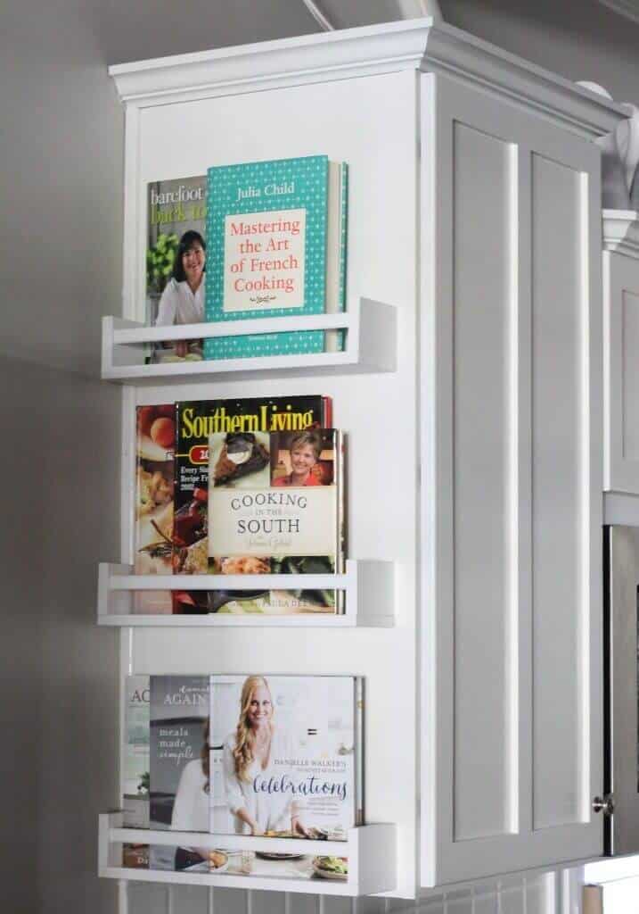 Wall-mounted, open-display shelves in white MDF, showcasing cookbooks and magazines, enhancing kitchen organization and aesthetics.