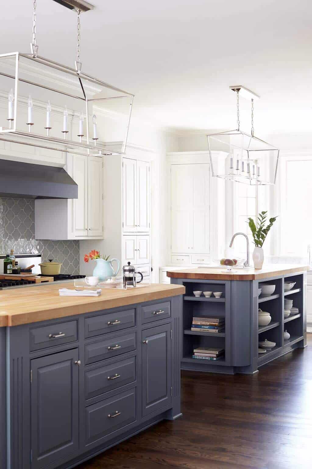 Spacious kitchen design featuring two islands: one with a wooden countertop and gray base, surrounded by chic cabinetry and pendant lights.
