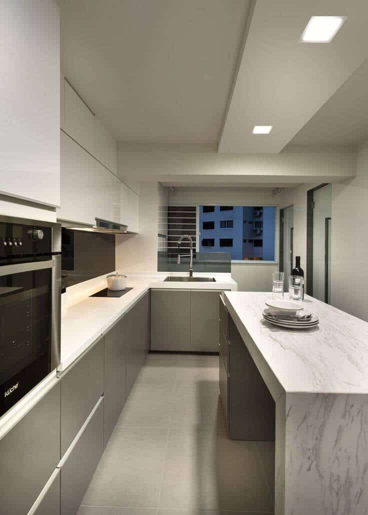 Modern kitchen with glossy gray cabinetry, central white marble island, and stainless steel appliances. Ideal for clever kitchen storage and organization.
