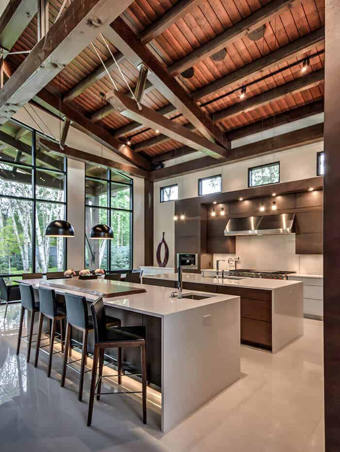 Spacious modern kitchen with two islands, featuring white quartz countertops, dark wood accents, and abundant natural light from tall windows.