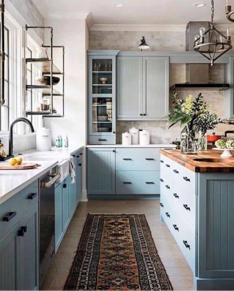 Light blue cabinetry with beadboard design complements a U-shaped layout featuring a 4x2.5 ft wood-topped island, enhancing kitchen functionality.