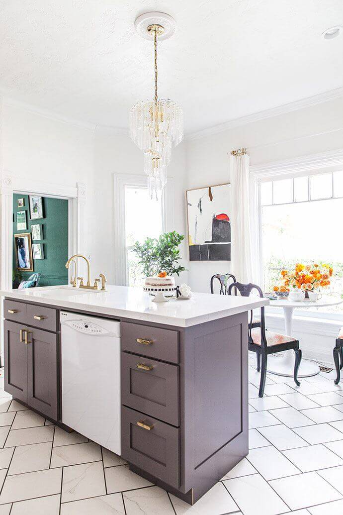 Kitchen design showcasing a central island with dark cabinetry and white marble countertop, built-in dishwasher, and elegant herringbone tile flooring.