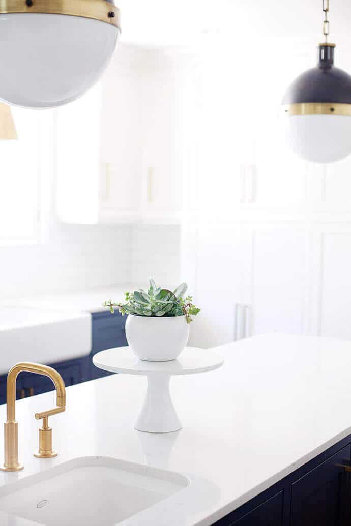Modern kitchen design featuring a spacious island with a white quartz countertop, undermount sink, and elegant gold-toned faucet.