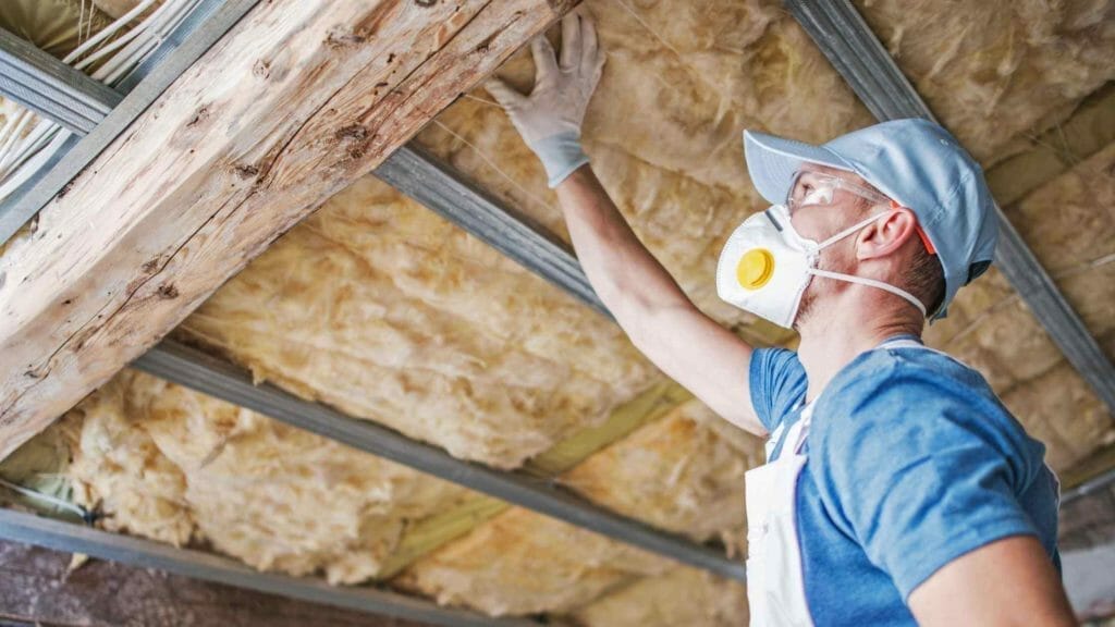 How to insulate a sunroom? (Explained) 3 Photo of a person applying rock wool insulation to the ceiling of a sunroom.